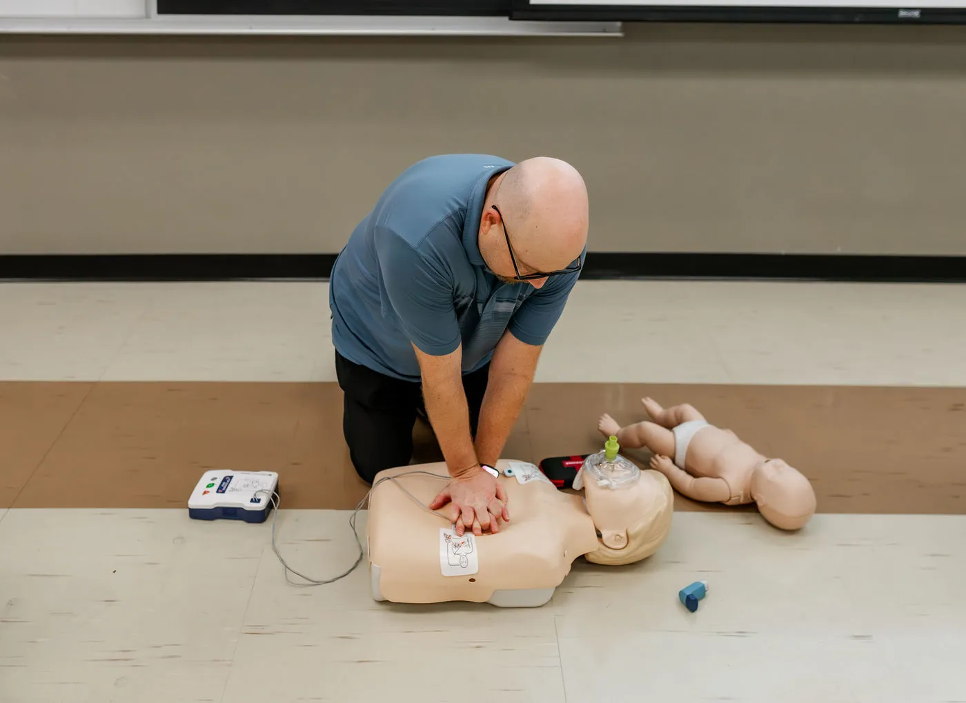 Instructor practicing CPR technique on a training mannequin.