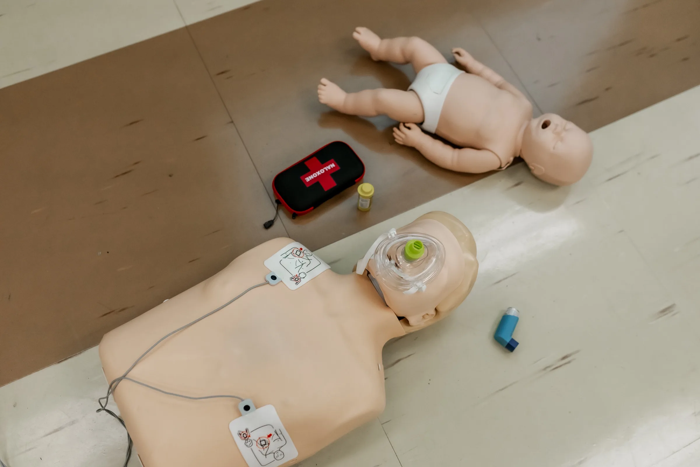 Adult and infant CPR mannequins set out with first aid training equipment.